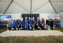 Mercer breaks ground on new medical school building in downtown Macon Eleven people in hard hats hold shovels at a groundbreaking ceremony under a tent with two display screens and a sand pile.