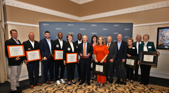 10th annual Alumni Awards Reception recognizes outstanding Mercerians A group of people stand indoors holding awards and framed certificates in front of a Mercer University backdrop.