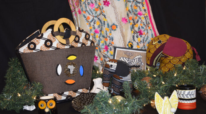 Holiday market to raise funds, visibility for Mercer On Mission Display of handmade crafts including bags, mugs, fabric animals, and greenery with a patterned cloth backdrop.