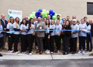 Kids Alliance for Better Care celebrates Dodge County Hospital’s emergency department as part of the Pediatric Emergency Care Project A group of people pose for a ribbon-cutting ceremony outside a building, with balloons and a kidsABC banner in the background.