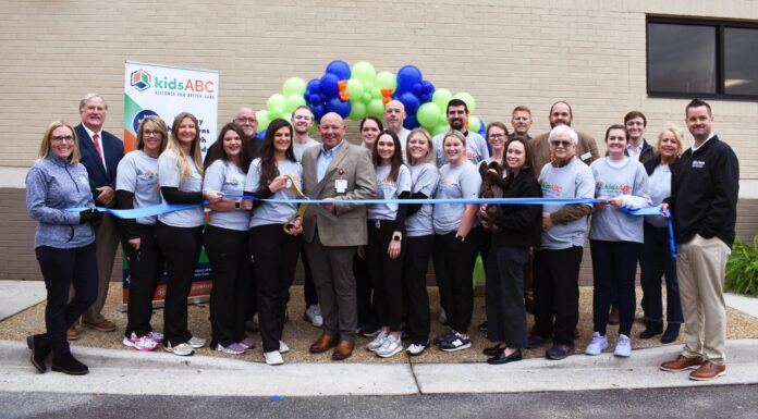 Kids Alliance for Better Care celebrates Dodge County Hospital’s emergency department as part of the Pediatric Emergency Care Project A group of people pose for a ribbon-cutting ceremony outside a building, with balloons and a kidsABC banner in the background.