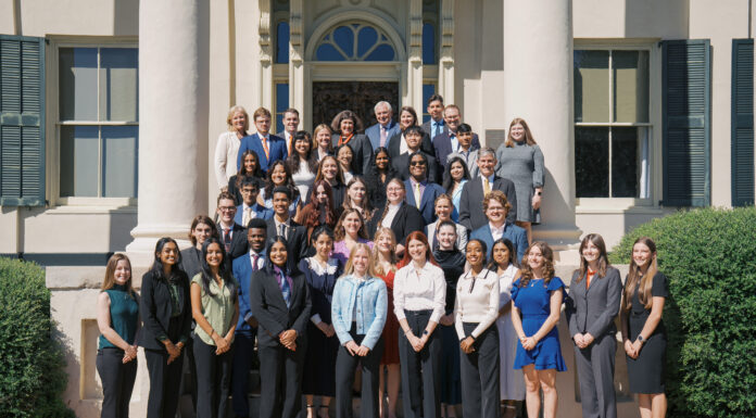 Mercer welcomes 14th class of Stamps Scholars A large group of people in formal attire poses for a group photo on steps outside a building with columns.