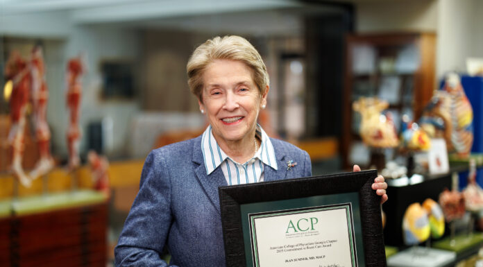 Georgia ACP establishes rural care award in School of Medicine dean’s name Dr. Jean Sumner holds a framed ACP certificate, standing in the MUSM medical library