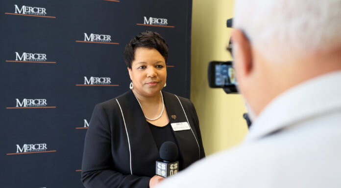 Dr. Loleta Sartin honored for contributions to teacher education A woman is interviewed on camera in front of a Mercer University backdrop, holding a microphone.