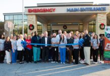 Kids Alliance for Better Care celebrates Colquitt Regional Medical Center’s emergency department as part of the Pediatric Emergency Care Project A group of people stands outside a hospital entrance, holding a large blue ribbon for a ribbon-cutting ceremony.