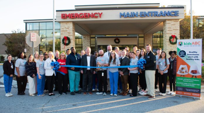 Kids Alliance for Better Care celebrates Colquitt Regional Medical Center’s emergency department as part of the Pediatric Emergency Care Project A group of people stands outside a hospital entrance, holding a large blue ribbon for a ribbon-cutting ceremony.