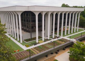Communication students develop social media strategy for Goodwill A modern, multi-story building with tall white columns and landscaped grounds, surrounded by trees.