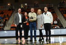 Cardelino, Steele honored on All-Southern Conference Faculty and Staff Team Five people stand on a basketball court during a ceremony, with one person holding a plaque and spectators in the background.