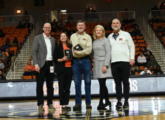 Cardelino, Steele honored on All-Southern Conference Faculty and Staff Team Five people stand on a basketball court during a ceremony, with one person holding a plaque and spectators in the background.
