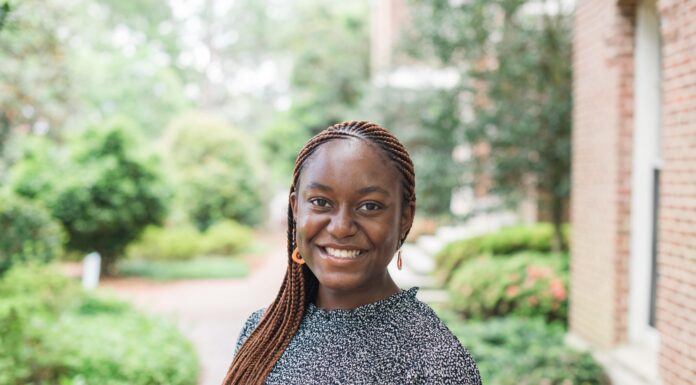 Mercerian selected for Duke Cancer Institute’s DIRECT Fellowship Young woman with braided hair smiles outdoors, standing near a brick building with greenery in the background.