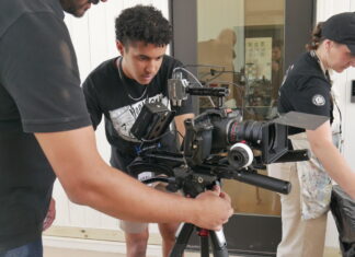 Mercer alumnus creates nonprofit for budding storytellers Three people set up and adjust a professional video camera mounted on a tripod indoors.