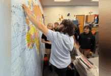 College of Education students see teaching in action at Roberts Academy A teacher points to a location on a world map while several students watch attentively in a classroom.