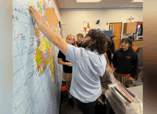 College of Education students see teaching in action at Roberts Academy A teacher points to a location on a world map while several students watch attentively in a classroom.