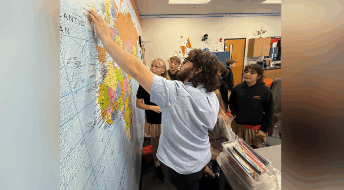 College of Education students see teaching in action at Roberts Academy A teacher points to a location on a world map while several students watch attentively in a classroom.
