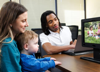 New program expands early autism diagnosis for children in rural Georgia A mother holds her child while he watches a video on the EarliPoint device while the technician oversees.