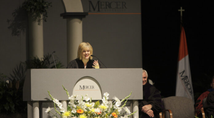 Nancy Grace to deliver 2026 Founders’ Day address A woman in academic regalia speaks at a podium decorated with flowers at a Mercer University event.