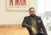 Center for Southern Studies to award 2026 Thomas Robinson Prize to poet, author Kevin Young A man with glasses sits at a wooden table beneath a framed sign that reads I AM A MAN in bold red letters.