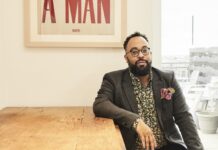 Center for Southern Studies to award 2026 Thomas Robinson Prize to poet, author Kevin Young A man with glasses sits at a wooden table beneath a framed sign that reads I AM A MAN in bold red letters.