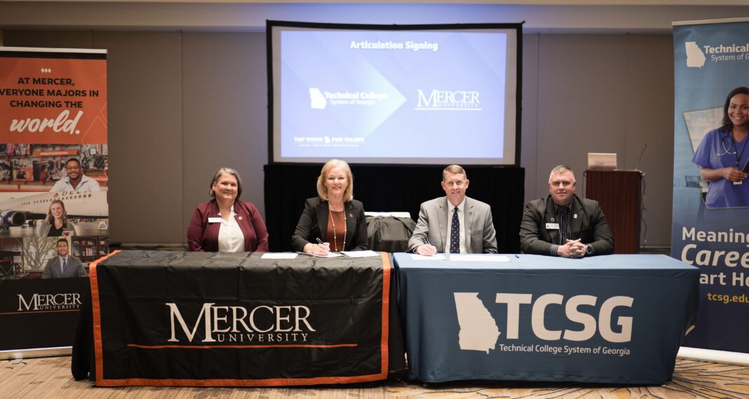 Four people sit at tables with Mercer University and TCSG logos, signing an articulation agreement in a conference room.