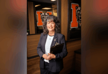 President Elkins appoints Dr. Maria Hammett as interim senior vice president for enrollment management A woman in business attire holds a clipboard, standing in an office with bear logos on glass walls behind her.