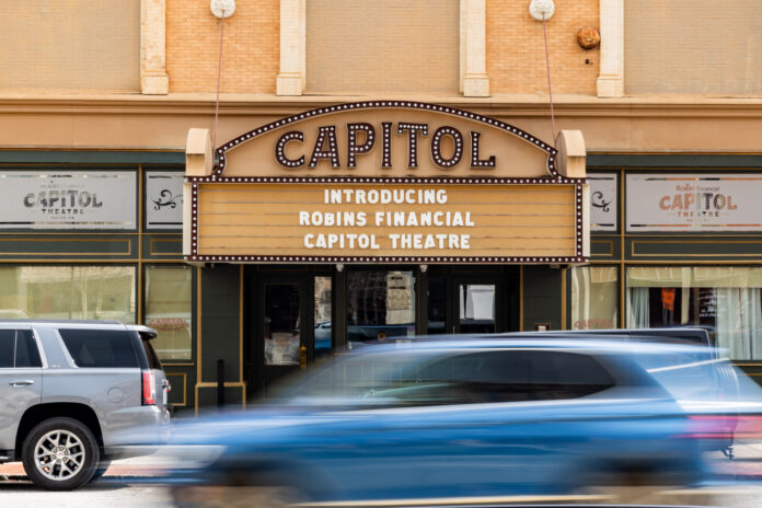 Capitol Theatre marquee reads Introducing Robins Financial Capitol Theatre with cars passing by in front.