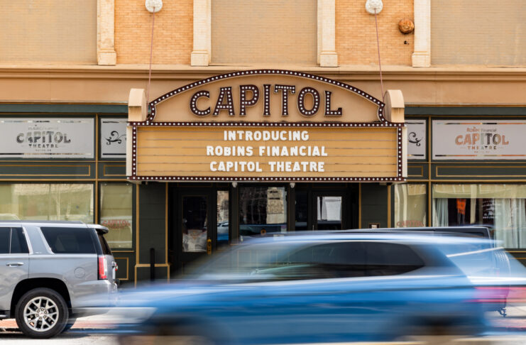 Capitol Theatre marquee reads Introducing Robins Financial Capitol Theatre with cars passing by in front.