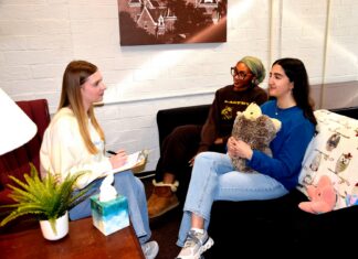 Mercer’s Macon campus launches peer counseling program Three women sit in a cozy room talking; one takes notes, while another holds a stuffed animal on the couch.