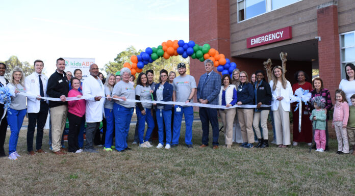 Kids Alliance for Better Care celebrates Wayne Memorial Hospital’s emergency department as part of Pediatric Emergency Care Project A group of people stand in front of an emergency room entrance, holding a ribbon for a ribbon-cutting ceremony.