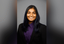 Sophomore awarded Fulbright Canada-Mitacs Globalink Research Internship A person with long dark hair, wearing a black blazer and purple shirt, smiles at the camera against a gray background.