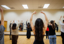 Spanish professor holds series on the art of flamenco A group of people practice dance in a mirrored studio, raising their arms in unison.
