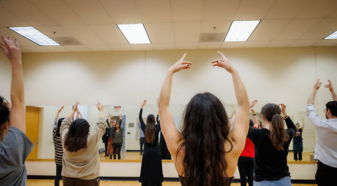 Spanish professor holds series on the art of flamenco A group of people practice dance in a mirrored studio, raising their arms in unison.