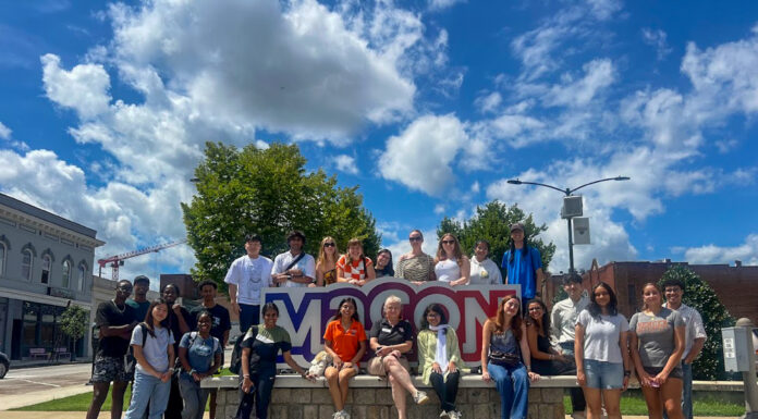 New mentorship program provides international students with extra support A group of people pose together outdoors in front of a large Macon sign on a sunny day.