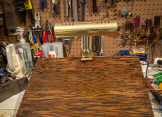 Pick up life’s pieces and mold them into something new | Dr. Craig McMahan A wooden desktop stand with a brass lamp on top, set on a workbench with various tools hanging in the background.