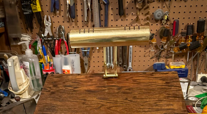 Pick up life’s pieces and mold them into something new | Dr. Craig McMahan A wooden desktop stand with a brass lamp on top, set on a workbench with various tools hanging in the background.