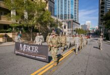 Mercer again leads the nation in Military Friendly® Rankings A group of people in military uniforms march on a city street holding a Mercer University banner.
