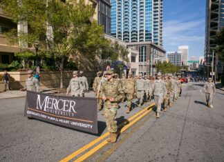 Mercer again leads the nation in Military Friendly® Rankings A group of people in military uniforms march on a city street holding a Mercer University banner.