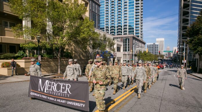 Mercer again leads the nation in Military Friendly® Rankings A group of people in military uniforms march on a city street holding a Mercer University banner.