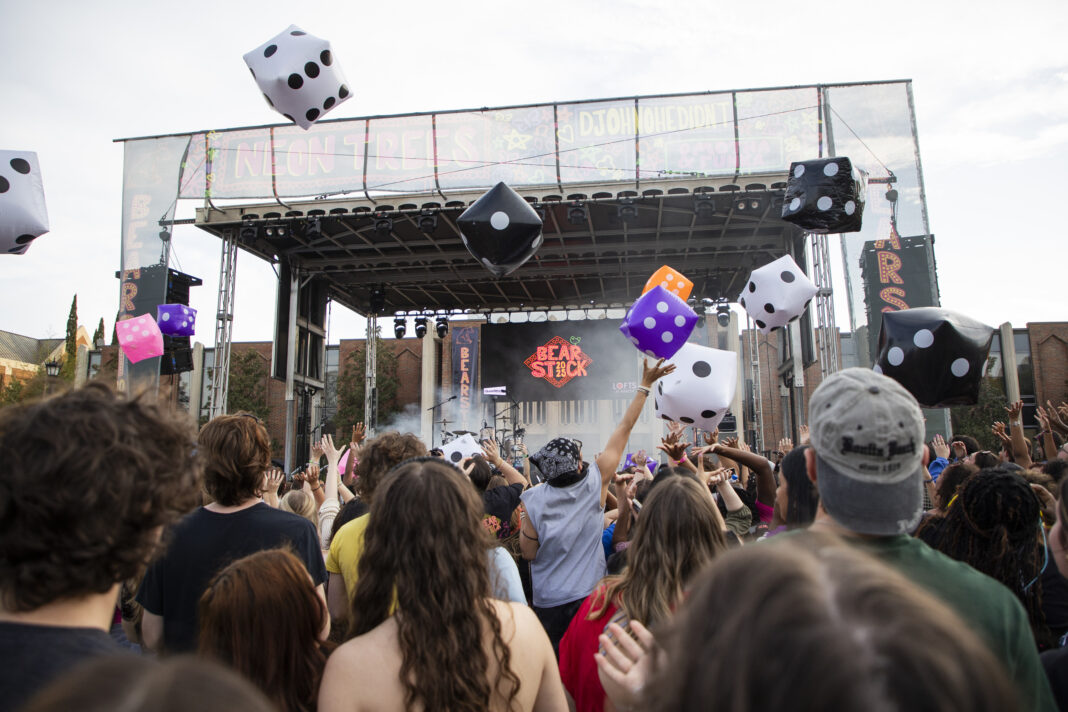 2025_Bearstock_jgratigny_0067 Outdoor concert crowd tosses large inflatable dice in front of a stage with Bear Stock on the screen.