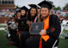 Mercer recognized for fostering student success from enrollment to post-graduation Mercer graduates in caps and gowns sit in rows holding diplomas during an outdoor graduation ceremony.