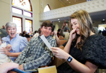 School of Medicine celebrates National Residency Match Day 2026 A young woman smiles and covers her mouth while reading a card, seated with two others in a church.