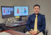Mercer pharmacy professor named Fellow of the American Heart Association Man in business attire sits at a desk with documents, glasses, and two monitors displaying medical diagrams behind him.