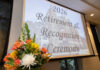 Faculty, staff honored at 2026 Retirement and Recognition Ceremonies A flower arrangement in front of a screen displaying 2026 Retirement & Recognition Ceremony in a conference room.