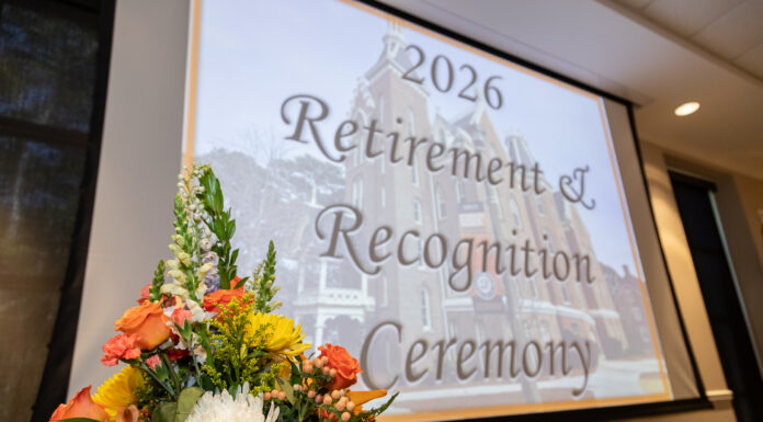 Faculty, staff honored at 2026 Retirement and Recognition Ceremonies A flower arrangement in front of a screen displaying 2026 Retirement & Recognition Ceremony in a conference room.