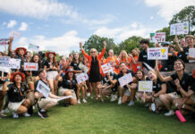 Mercer president proud to lead the university that changed her life A group of smiling young people, mostly in black shirts and khaki shorts, hold up signs with various names and drawings.