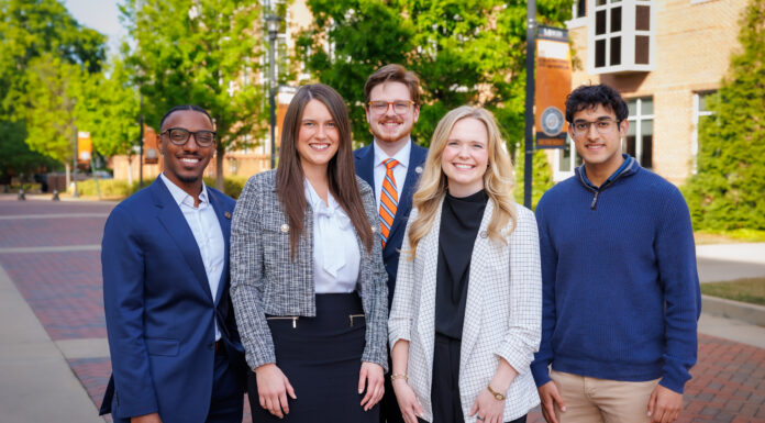 Fellows build leadership, character while working alongside Mercer president Five professionally dressed people stand and smile outside on a brick walkway with trees and buildings in the background.