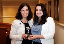 French professor forges new pathways for students Two women standing indoors, smiling and holding a star-shaped award together in front of a podium.