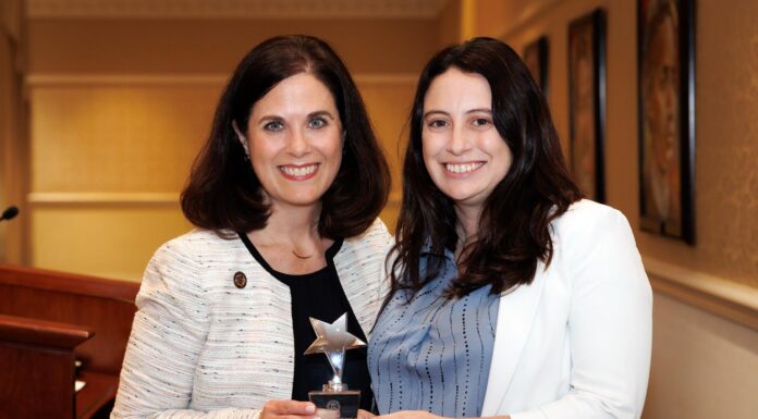 French professor forges new pathways for students Two women standing indoors, smiling and holding a star-shaped award together in front of a podium.