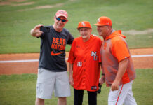 ‘Bloody Mary’ throws first pitch at Mercer baseball game Three people in Mercer University baseball attire pose for a selfie on a baseball field near the foul line.