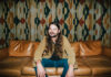 Brent Cobb hosts 2nd South of Atlanta Fest at Robins Financial Capitol Theatre Brent Cobb sits on a leather couch in front of patterned curtains.