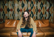 Brent Cobb hosts 2nd South of Atlanta Fest at Robins Financial Capitol Theatre Brent Cobb sits on a leather couch in front of patterned curtains.